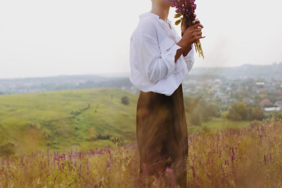 Woman in a field smelling a bouquet of lavender flowers