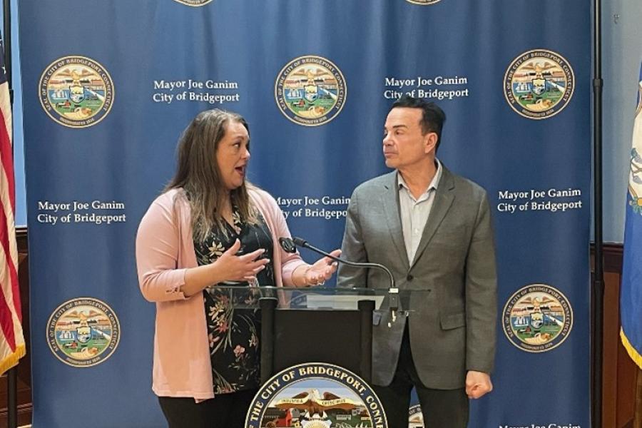 Mayor Ganim and Dr. Rivera-Rodriguez standing at the City of Bridgeport podium in the Mayor's Back Conference Room, discussing the grant awarded by the U.S. Conference of Mayors
