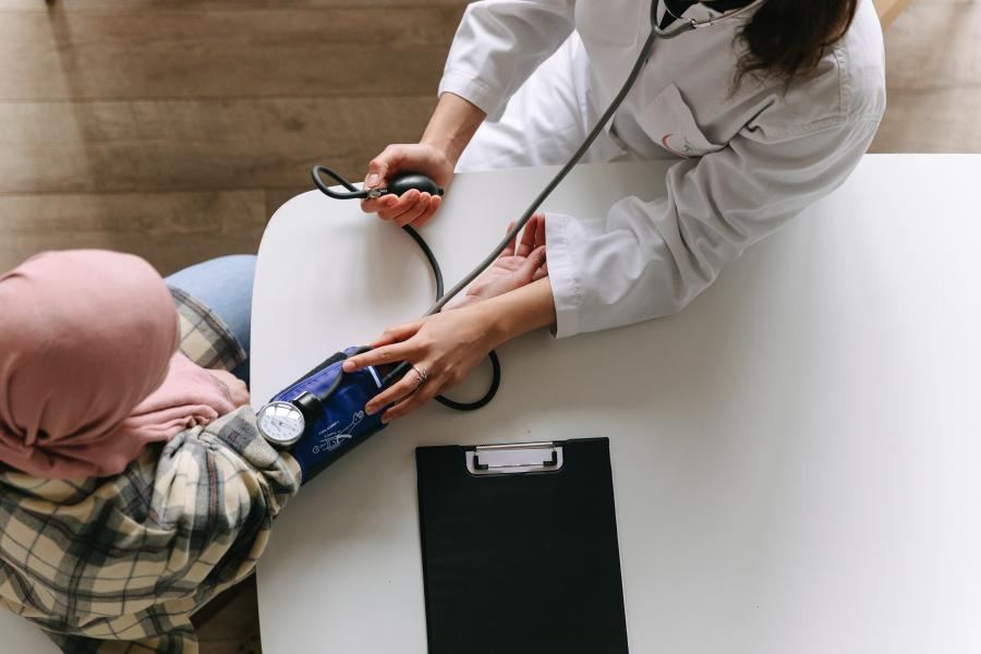 Overhead view of one person taking the blood pressure reading of another using an arm cuff.