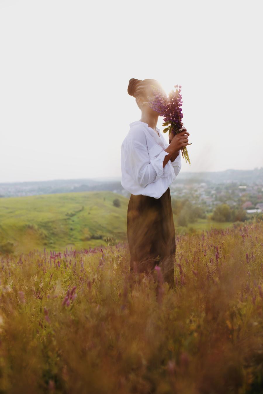 Woman in a field smelling a bouquet of lavender flowers