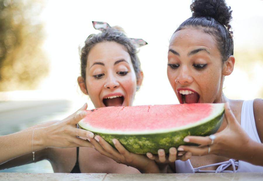 Two women about to bite into a large slice of watermelon